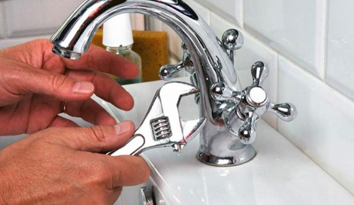 Worker repairing leaky faucet and fixtures